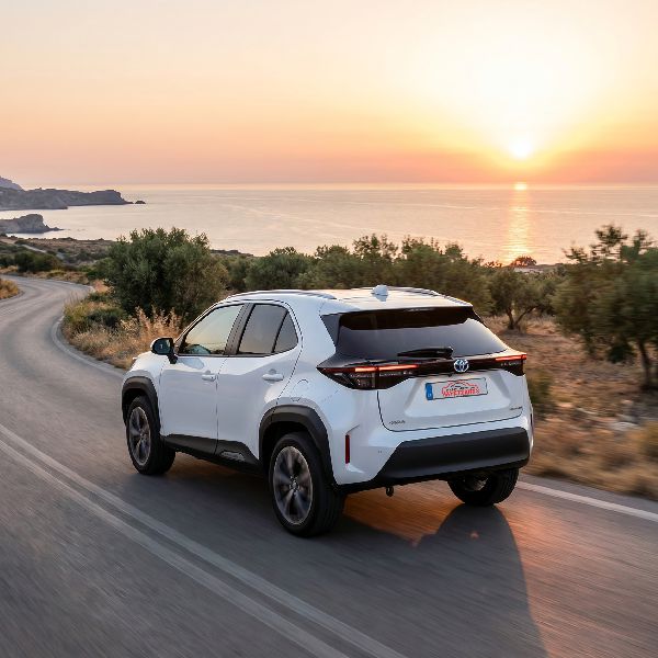 SUV rental car driving on Cretan coastal road with sunset over the sea